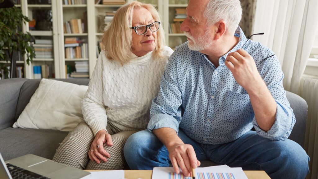 Retired couple discussing concerns and paperwork together at home.