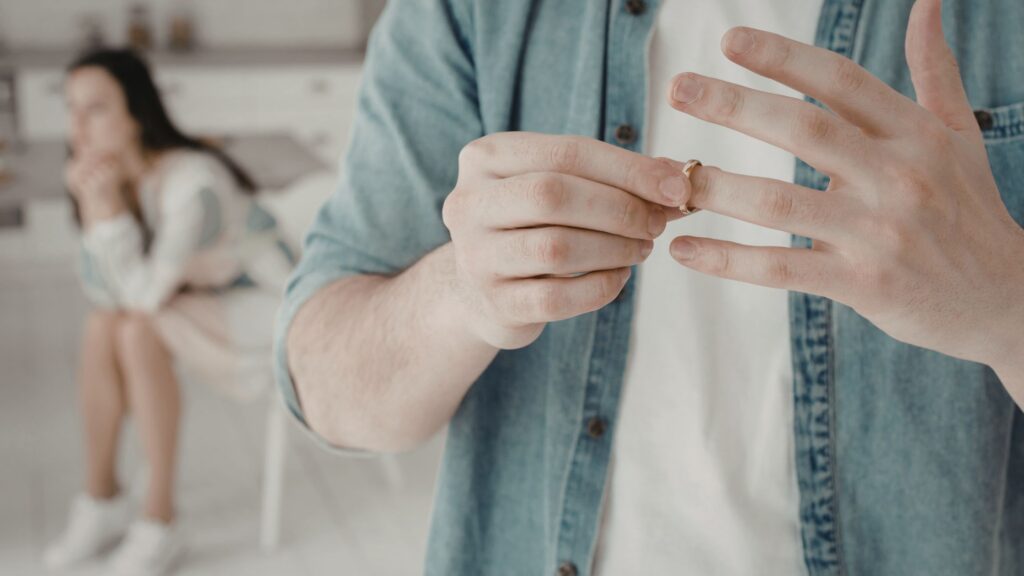 Individual removing a wedding ring while navigating divorce.