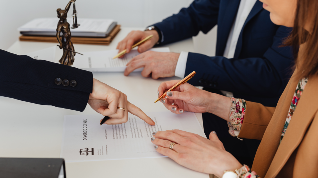 Couple reviewing divorce documents with an attorney and Lady Justice statue on the desk