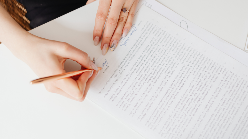 Woman signing a divorce financial agreement document with a rose gold pen