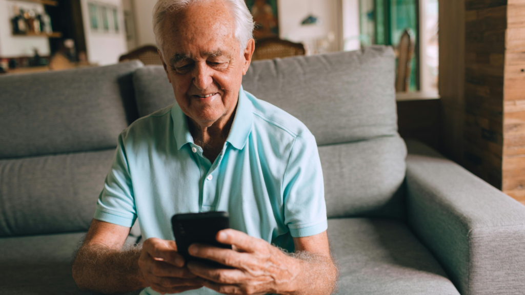 Retired man sitting on a couch looking at his phone while researching retirement lifestyle planning options