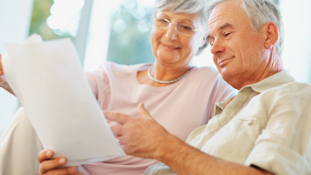 Retired couple reviewing retirement planning documents together at home in natural light