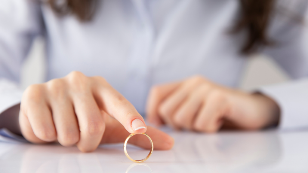 Woman placing a wedding ring on a table while considering divorce financial preparation